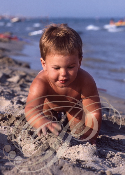ENFANT de 18 mois jouant dans le sable au bord de la mer